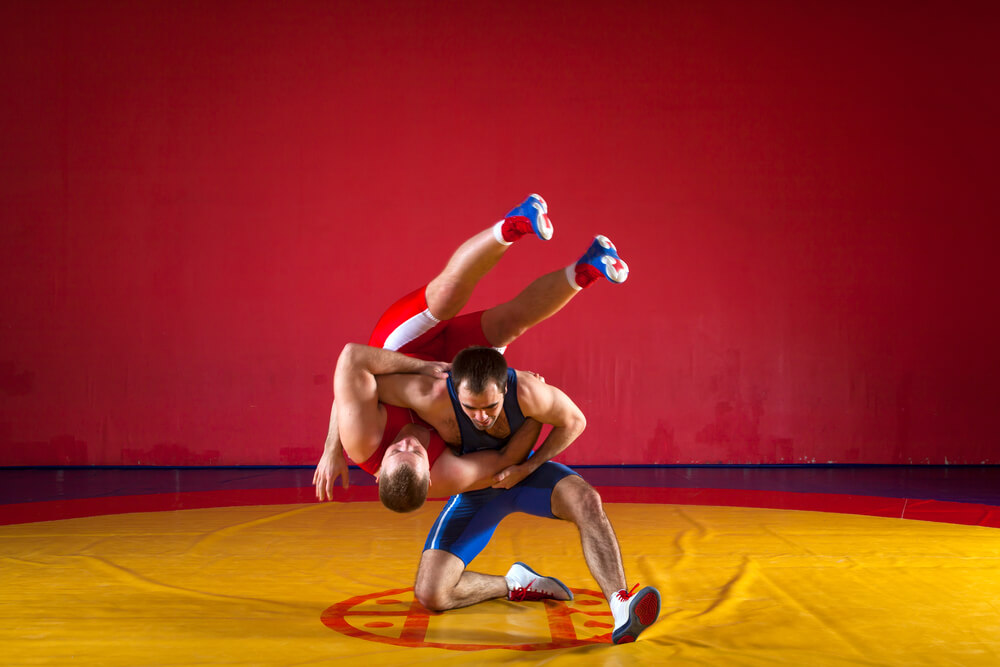 Two young men in blue and red wrestling tights are wrestlng